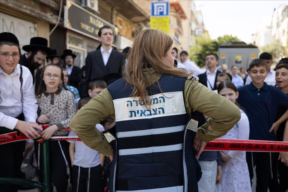 קהל מאחורי סרט תיחום ואישה במדים בחזית